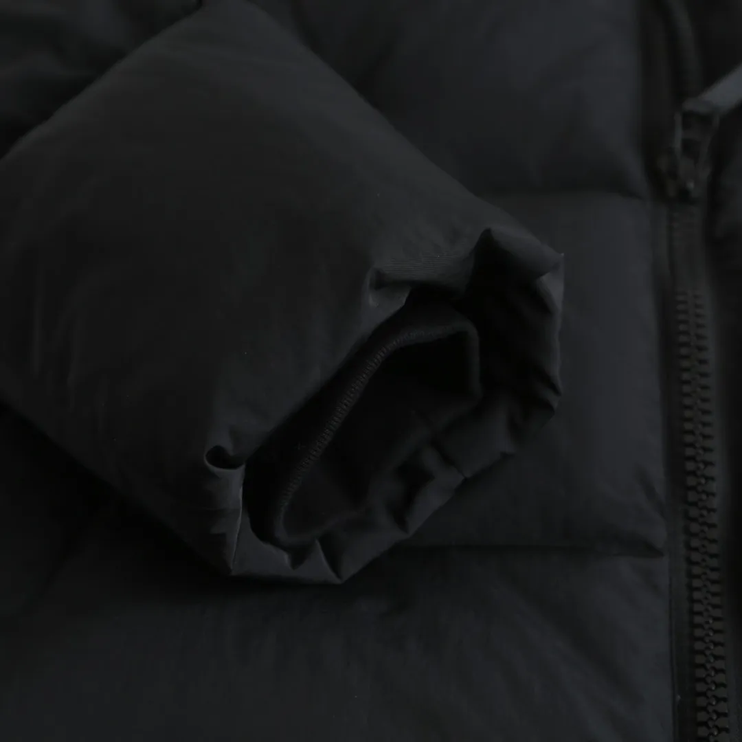 P980 Canada Goose hooded down jacket Fabric selection: Weaved with 400T high-count yarn. After special water-repellent treatment, the surface forms a lotus leaf effect - raindrops will slide down in beads, and snow particles will fall off when touched. The tear resistance reaches 200N (approximately 20kg load-bearing), the light gray matte texture breaks the stereotype of "outdoor clothing = hardcore", and the soft luster presents a high-end matte effect under urban neon lights, seamlessly switching scenes from ski resorts to CBD office buildings.  Process 1: Use polyester woven ribbons as the base, and use high-precision computer embroidery to decorate the brand letters on the ribbons. The edges of the pattern are clear, the stitches are fine and even, and multiple layers of embroidery threads are stacked to enhance the three-dimensional effect.  Process 2: Precision thread reinforcement to prevent velvet drilling and ensure that the fluffy and resilient elasticity lasts as new.  Details: The embedded cuffs are three-dimensionally woven to form a "wavy" elastic structure, forming natural folds when fitting the wrist, increasing the contact area with the skin, thus improving the windproof effect. At the same time, micro-velvet treatment is added to the inside of the cuffs, which feels like a second layer of skin and avoids friction on the skin from metal zippers or hard fabrics.  90 national standard high-quality white duck down: selected high-loft down, weighing 240g, light and warm, with excellent temperature locking performance and good resilience.  Accessories: 1:1 customized armband, 1:1 customized zipper pendant, 1:1 customized elastic buckle, etc. SIZE: S M L XL